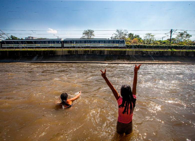 Niñas migrantes se bañan en las aguas contaminadas del río Medellín. FOTO: Esneyder Gutiérrez. 