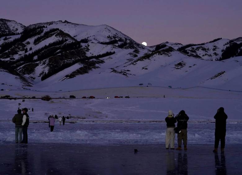 Turistas toman fotografías de la luna en la superficie helada del lago Sayram, en el noroeste de China. FOTO: Getty