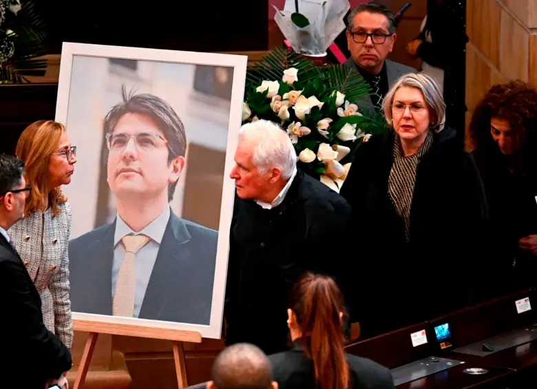 Miguel Uribe Londoño junto a la foto de su hijo, Miguel Uribe Turbay, en el Salón Elíptico del Congreso donde será la cámara ardiente del político de 39 años. FOTO: AFP
