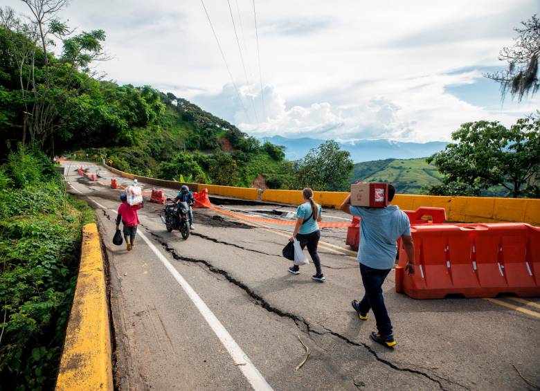 Cargando maletas y bultos, los viajeros deben cruzar al otro lado del maltrecho puente en busca del transbordo. FOTO: Camilo Suárez.