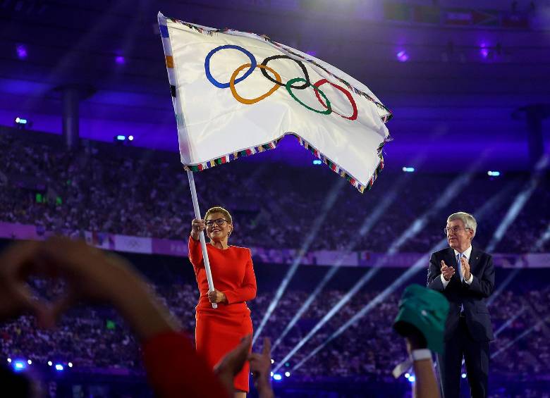 Karen Bass, alcaldesa de Los Ángeles, ondea la bandera olímpica mientras Thomas Bach, presidente del Comité Olímpico Internacional, aplaude durante la ceremonia de clausura de los Juegos. FOTO: GETTY