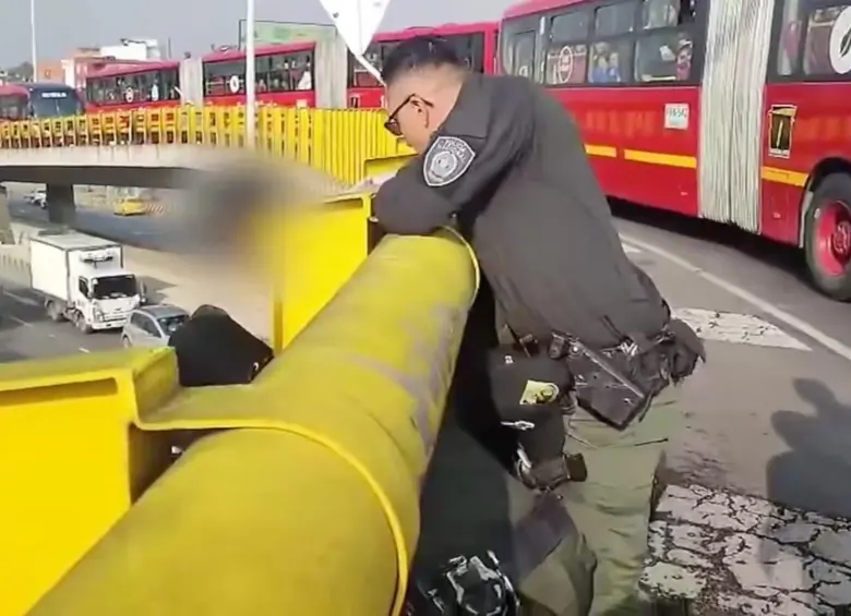 El policía sosteniendo al joven para que no se tirara del puente. FOTO: Captura de video de redes sociales @PoliciaBogota