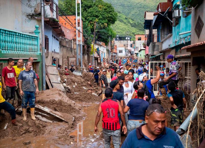 Personas retiran escombros en la zona donde ocurrió el desbordamiento de la quebrada Los Patos, en Las Tejerías, estado Aragua. FOTO: EFE