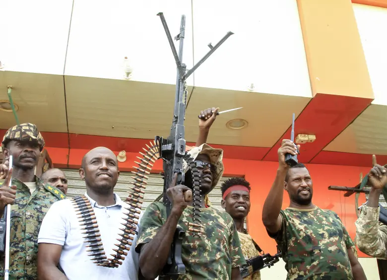 Un hombre posa con soldados del ejército sudanés en Salha, al sur de Omdurman, un día después de haber recuperado la zona de manos de las fuerzas paramilitares de Apoyo Rápido (RSF), el 21 de mayo de 2025. Desde su estallido en 2023, Sudán ha sido devastado por la guerra entre las RSF y el ejército, alimentada por intereses regionales contrapuestos que incluyen a los Emiratos Árabes Unidos, Egipto, Arabia Saudita e Irán. Mercenarios extranjeros han aparecido en ambos bandos del conflicto. (Foto de Ebrahim Hamid / AFP)