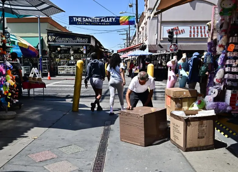 Un comerciante abre cajas frente a un negocio a lo largo de Santee Alley en el distrito de la moda del centro de los Ángeles. El barrio se ha convertido en una ciudad fantasma en medio de redadas de agentes del Servicio de Inmigración y Control de Aduanas (ICE). FOTO: AFP