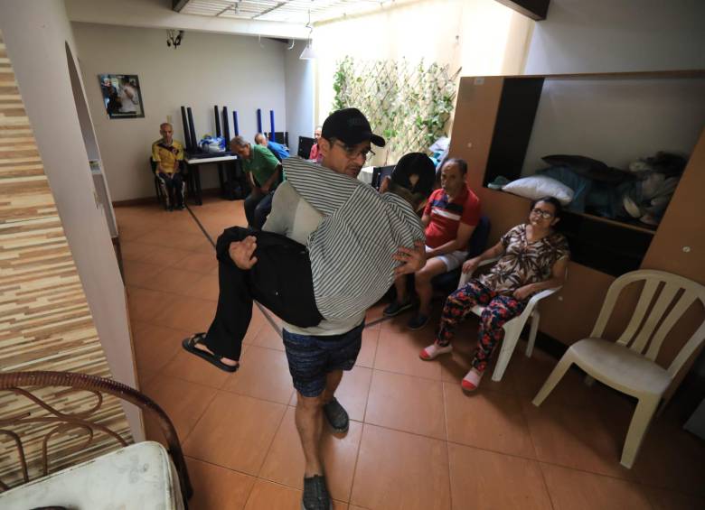 José Ávila, el director de Sembradores de Esperanza dedica sus días y noches al hogar. Lleva en sus brazos a uno de los adultos mayores con movilidad reducida. FOTO: Esneyder Gutiérrez