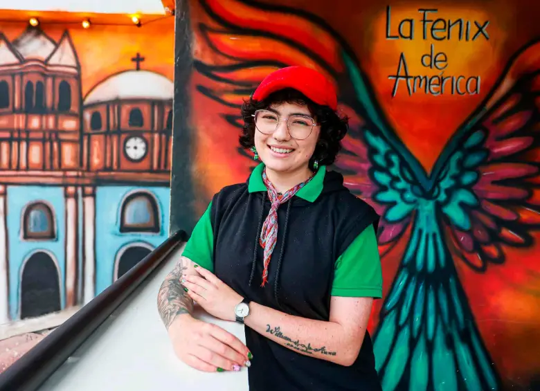 Daniela posa frente a uno de los murales que ha hecho en El Peñol. Su trabajo hace énfasis en la historia del municipio. FOTO Manuel Saldarriaga