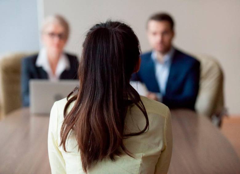 Mujer realizando una entrevista de trabajo en una mesa frente a dos reclutadores. FOTO: Shutterstock