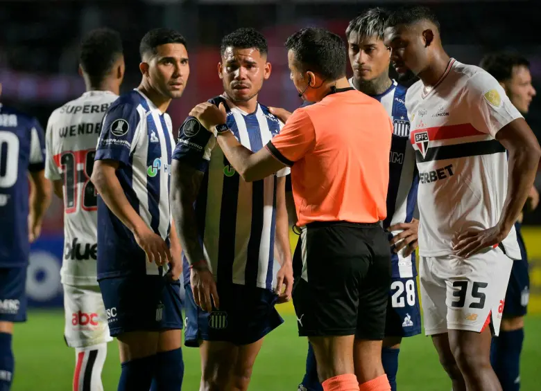 Miguel Navarro, de Talleres, junto al árbitro chileno Piero Maza. FOTO: AFP