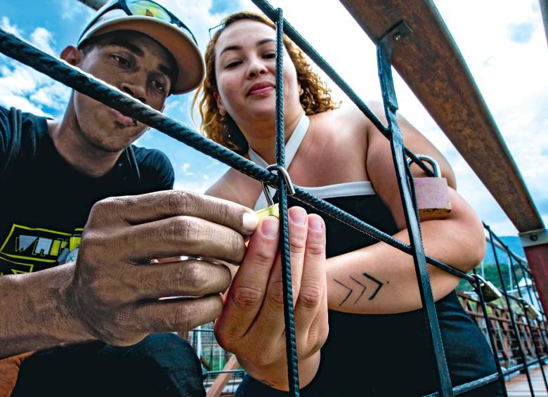 David Mesa y Jeimy Montoya, en el momento en que realizaban el ritual del candado en el Puente de Occidente. Lo hicieron a hurtadillas, como si temieran ser castigados. FOTO Julio César Herrera