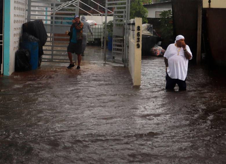 Personas caminan en una calle inundada debido a lluvias ocasionadas por el paso del huracán Fiona. FOTO: EFE