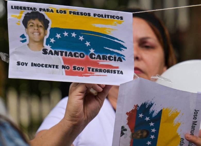 Una mujer cuelga fotografías de presos políticos en una cuerda durante una vigilia exigiendo su liberación frente a la Corte Suprema de Justicia en Caracas. FOTO: AFP