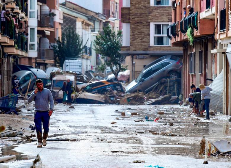 Habitantes observan vehículos y escombros tras las devastadoras lluvias. FOTO: AFP