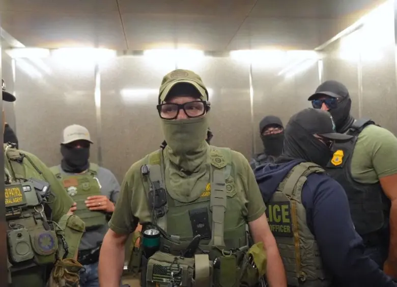 Agentes federales de inmigración patrullando los pasillos de un edificio federal. FOTO: AFP