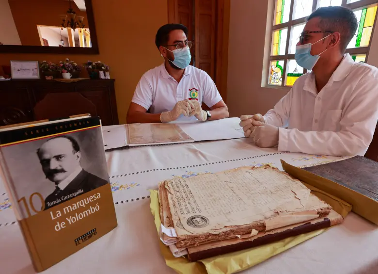 Francisco Gómez y Carlos Vanegas revisan los archivos parroquiales de Yolombó, en los que aparecen algunos personajes de la ficción. Foto>: Manuel Saldarriaga.