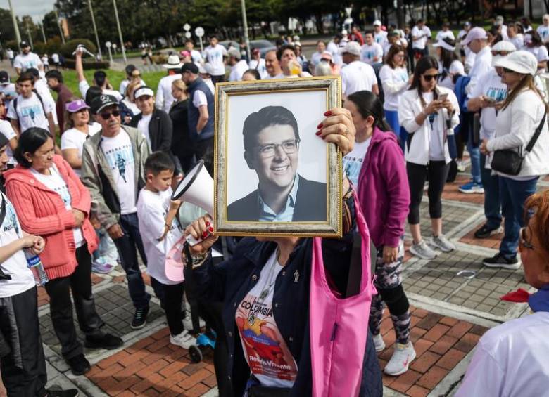 Una mujer sosteniendo un cuadro con el rostro de Miguel Uribe en la “Carrera por la Vida”, en respaldo a la salud del senador. FOTO: COLPRENSA