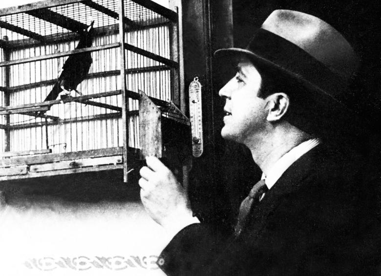 Foto tomada en 1930 muestra al cantante de tango observando un pájaro en una jaula. FOTO AFP