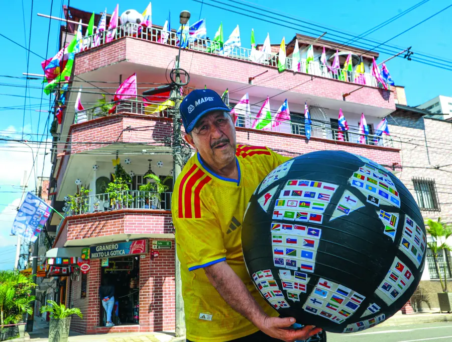 Don Gustavo posando con el ‘balón mundialista’, decorado con más de 300 banderas de las selecciones que han participado a lo largo de la historia en las copas mundiales de fútbol. FOTO Manuel Saldarriaga. 