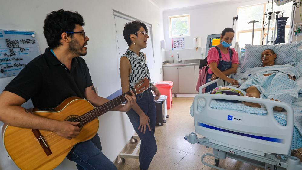 Los músicos María José Sánchez y Anderson Medina Ríos le dan una serenata a Omaira Montoya quién se encuentra internada en la Unidad de Cuidados Intensivos acompañada de su hija Diana Castaño. Foto: MANUEL SALDARRIAGA QUINTERO.