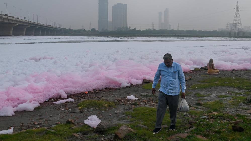 Un hombre camina a orillas del río Yamuna cubierto de espuma tóxica. Foto: Getty