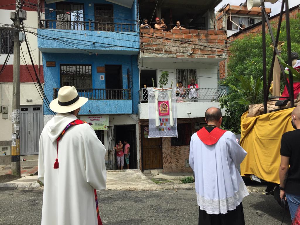 En el Barrio La Milagrosa, de la comuna 9 de Medellín, la iglesia organizó una procesión solitaria donde imparte la palabra acompañada de la policía. Los feligreses salen a los balcones al paso de la procesión. Foto: Edwin Bustamante.