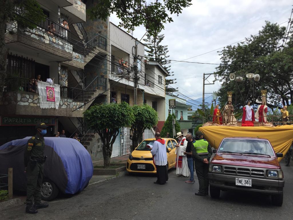 En el Barrio La Milagrosa, de la comuna 9 de Medellín, la iglesia organizó una procesión solitaria donde imparte la palabra acompañada de la policía. Los feligreses salen a los balcones al paso de la procesión. Foto: Edwin Bustamante.