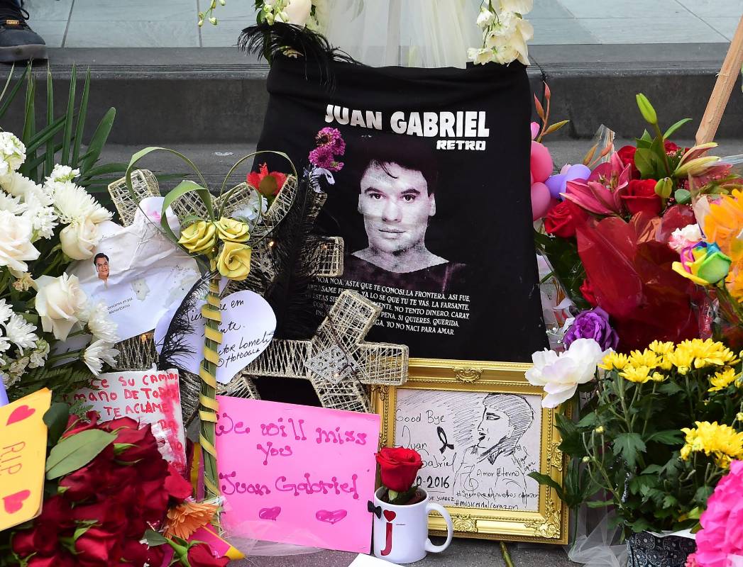La estrella en el Paseo de la Fama de Hollywood de Juan Gabriel, convertida en objeto de peregrinaje tras el fallecimiento este domingo del “Divo de Juárez”, se volvió a llenar de flores, lágrimas y rancheras a la espera de que se confirmen detalles sobre su funeral y homenajes oficiales. FOTO AFP