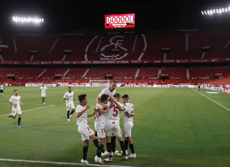 Los jugadores del Sevilla celebran el primer gol del partido. A pesar de las recomendaciones para no abrazarse y mantener la distancia, la emoción hace que no se cumplan. FOTO EFe 