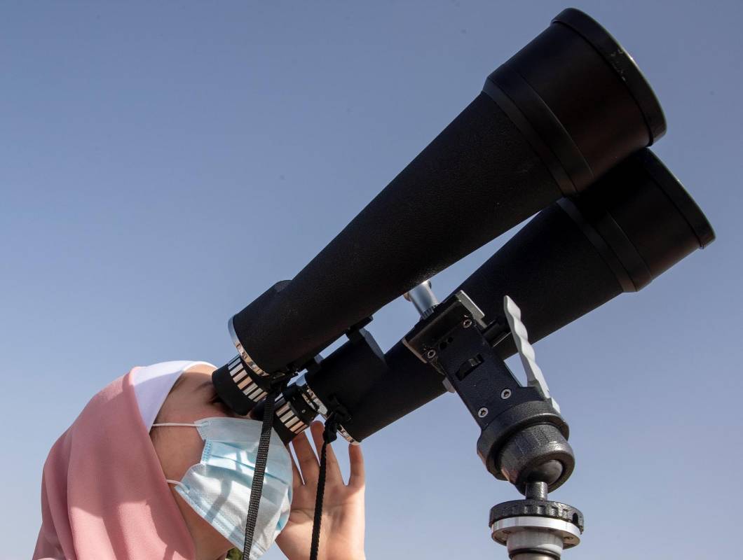Una mujer observa el eclipse solar con unos prismáticos de gran formato en Amman, Jordania. FOTO EFE
