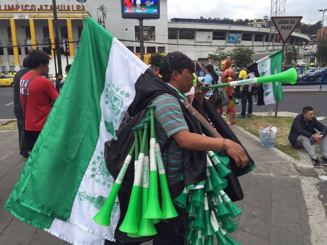 A las afueras del estadio Olímpico Atahualpa, los comerciantes aprovechan para vender banderas, pitos y demás productos alusivos a ambos equipos justo antes de que comience el primer encuentro de la final. FOTO Esteban Vanegas