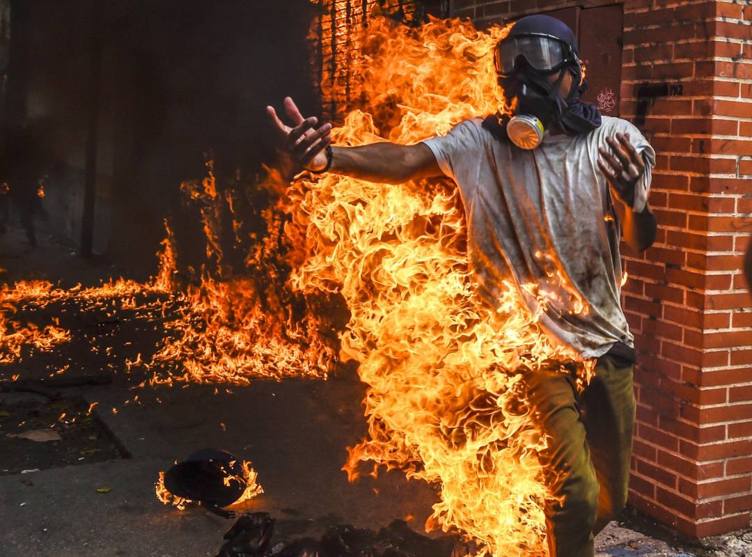 Manifestante de la oposición envuelto en llamas tras la explosión de un tanque de gasolina de una moto perteneciente a un funcionario de seguridad del estado. AFP