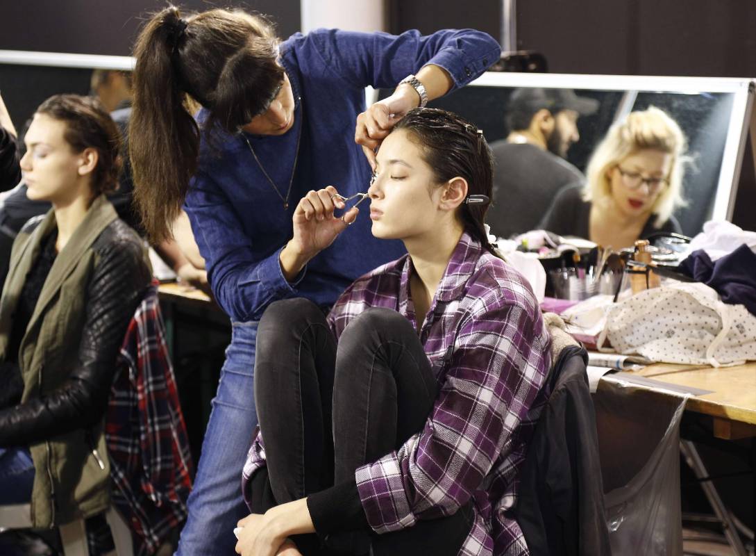 Maquilladora prepara un modelo en el backstage. FOTO AFP
