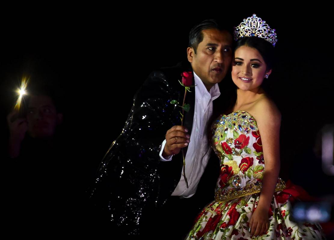 Como toda quinceañera, disfrutó del llamado vals de las 15 rosas y también se despidió de su ultimo juguete, una muñeca, mientras danzaba con su progenitor para escenificar la transición de niña a mujer. FOTO AFP
