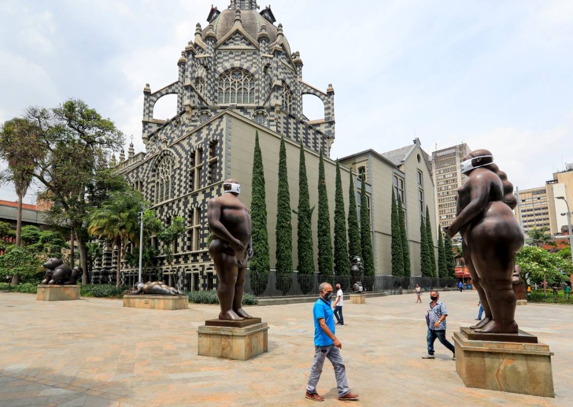 En la Plaza Botero, en inmediaciones del Museo de Antioquia, los rostros de las tradicionales figuras del maestro Fernando Botero fueron cubiertos con tapabocas. FOTO JAIME PÉREZ
