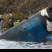 AP - En el lugar del accidente, un fragmento roto del fuselaje azul claro del avi&#243;n yac&#237;a medio sumergido en un r&#237;o.