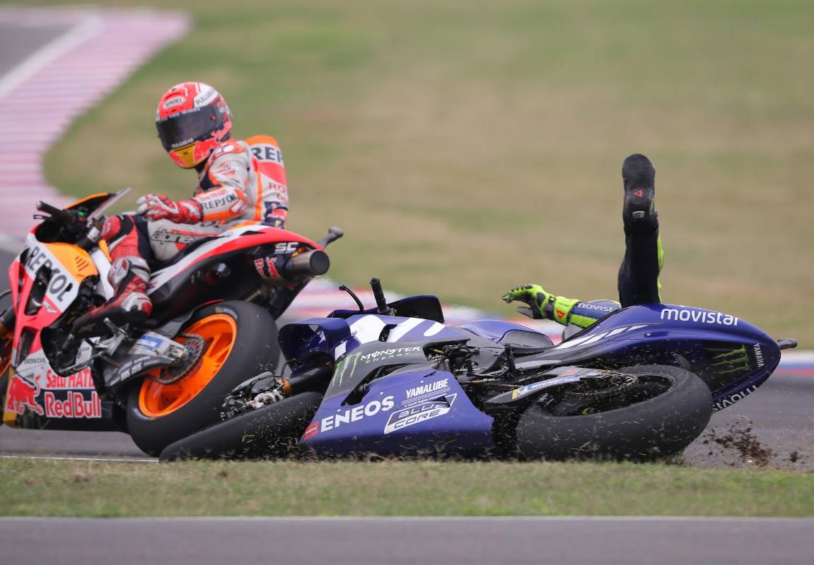 El piloto italiano de MotoGP Valentino Rossi (d), cae al piso en la última curva del circuito tras un toque con el piloto Marc Márquez, del equipo Repsol Honda Team.