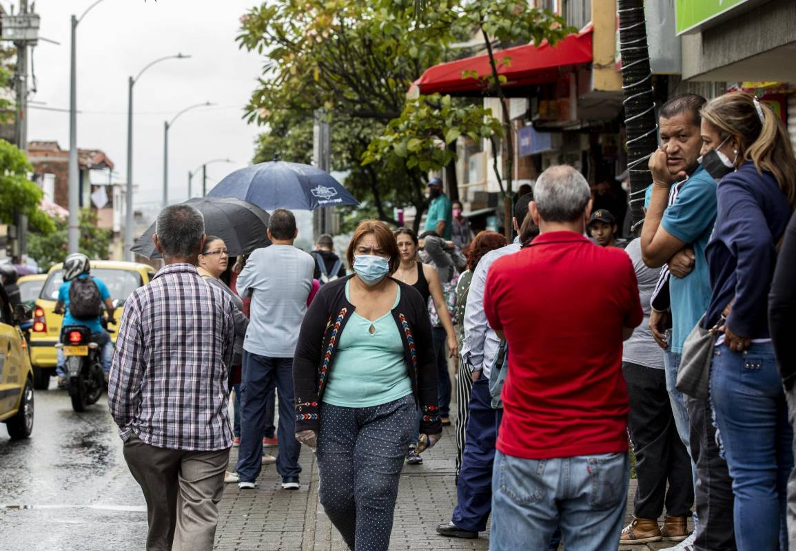 En el barrio Castilla personas escudadas detrás de un tapabocas hacen largas filas en los locales comerciales que están abiertos. Foto Julio César Herrera