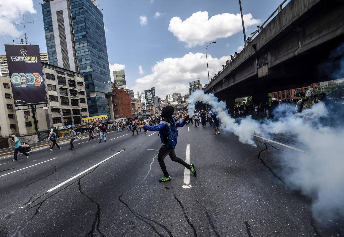 La Policía Nacional Bolivariana (PNB) dispersó hoy con gases lacrimógenos y agua una marcha opositora en Caracas que pretendía llegar hasta la Defensoría del Pueblo para pedir su respaldo al proceso iniciado por el Parlamento contra siete magistrados del Tribunal Supremo de Justicia (TSJ). FOTO AFP