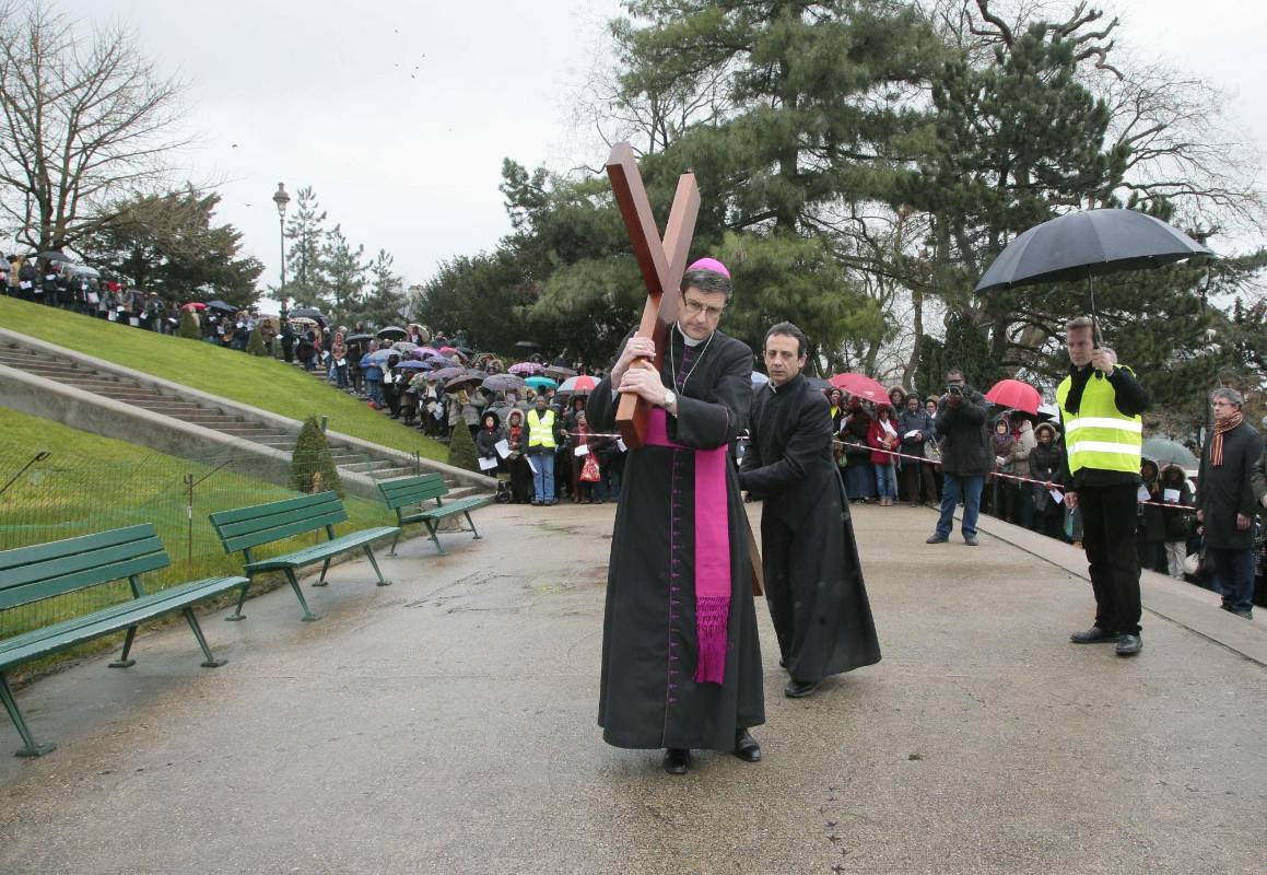 El obispo auxiliar de Paris, Eric de Moulins-Beaufort, hace las veces de Jesucristo acarreando la cruz durante el viacrucis de este viernes santo en el parque aledaño a la basílica del Sacre-Coeur de Montmartre (Paris). FOTO AFP 