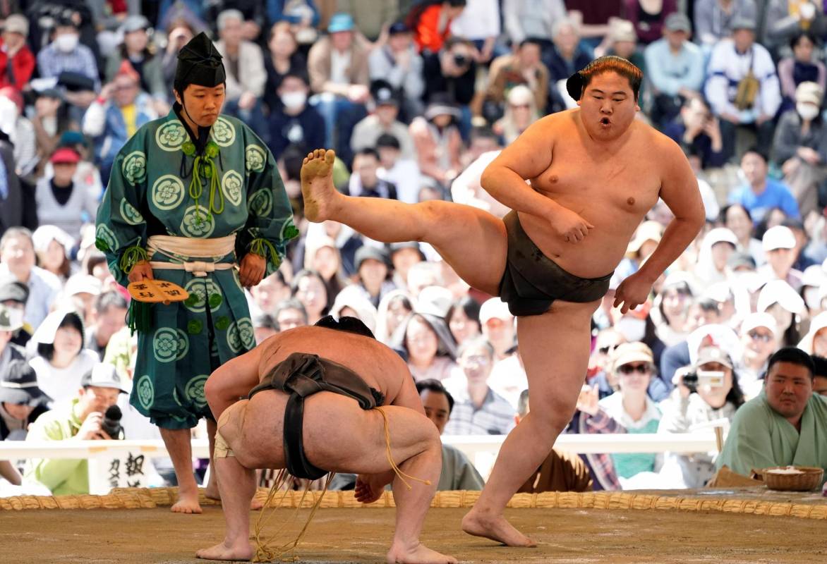 Dos luchadores de sumo realizan acrobacias durante una exhibición de “shokkiri” durante el “Honozumo”, un torneo ceremonial de sumo en los terrenos del santuario Yasukuni de Tokio. Foto: EFE/ Franck Robichon 