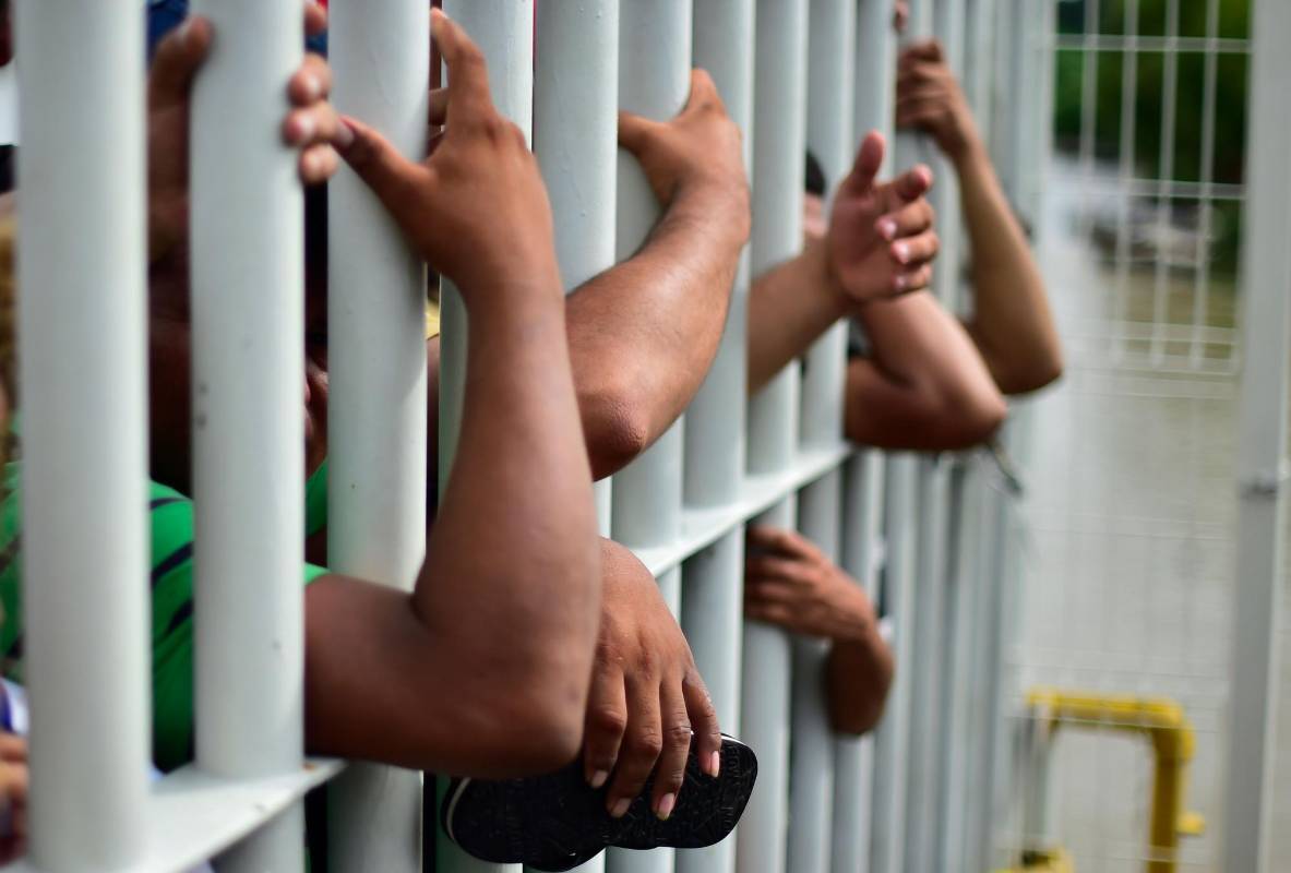 Miles de migrantes hondureños, que salieron en caravana de su país con destino a Estados Unidos, viven una tensa espera en el puente fronterizo entre México y Guatemala. AFP
