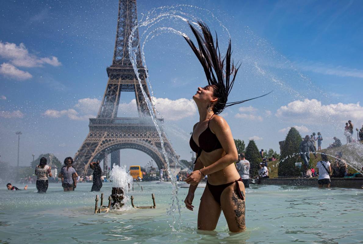 Una mujer se refresca con el agua de la fuente de la Plaza del Trocadero, frente a la Torre Eiffel, durante la ola de calor que recorre París. Las temperaturas llegarán a los 40 grados centígrados esta semana. Foto: EFE