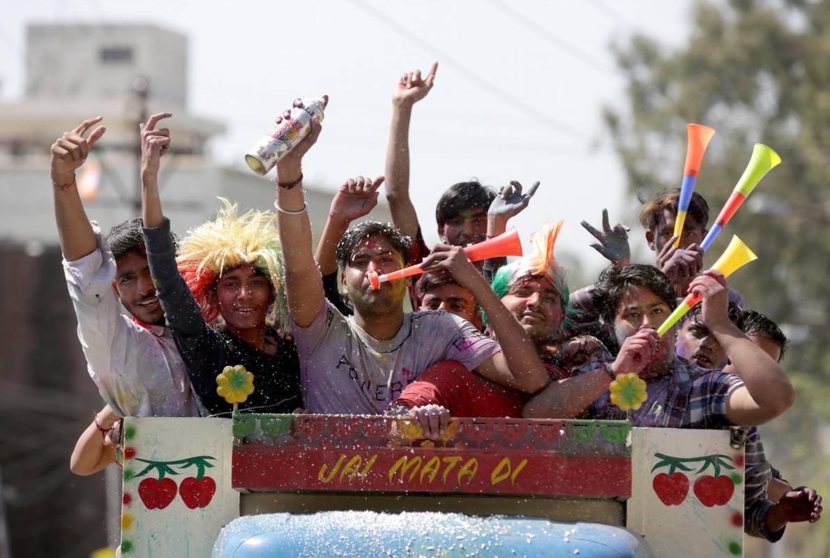 Los jóvenes sonríe embadurnados de colores mientras una multitud celebra, este miércoles, el festival Holi. Foto: EFE/ Divyakant Solanki