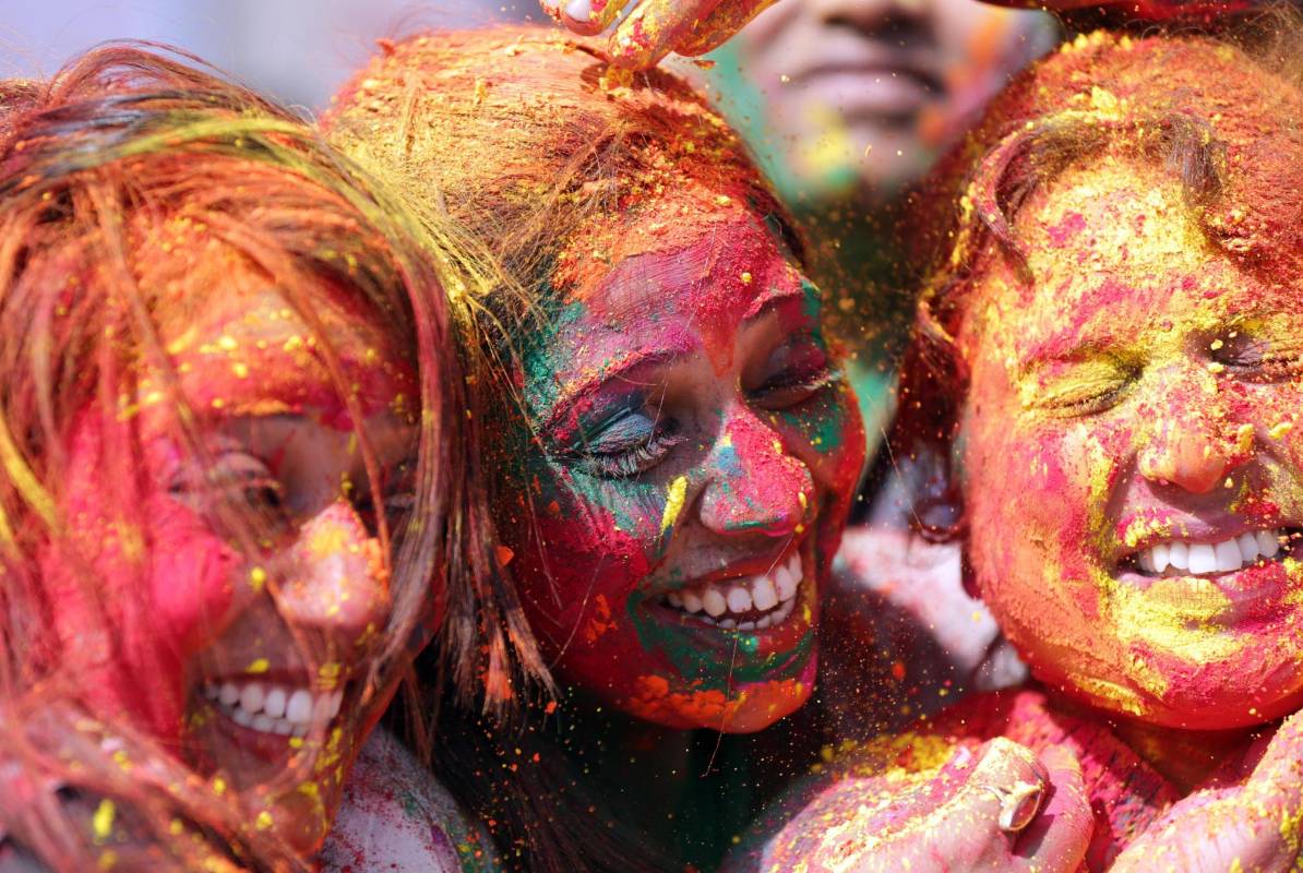 Los jóvenes sonríe embadurnados de colores mientras una multitud celebra, este miércoles, el festival Holi . Foto: EFE/ Divyakant Solanki