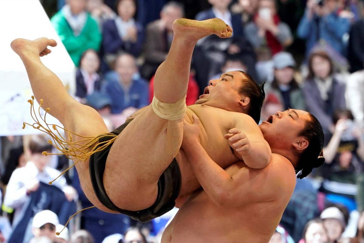 Dos luchadores de sumo realizan acrobacias durante una exhibición de “shokkiri” durante el “Honozumo”, un torneo ceremonial de sumo en los terrenos del santuario Yasukuni de Tokio. Foto: EFE/ Franck Robichon 