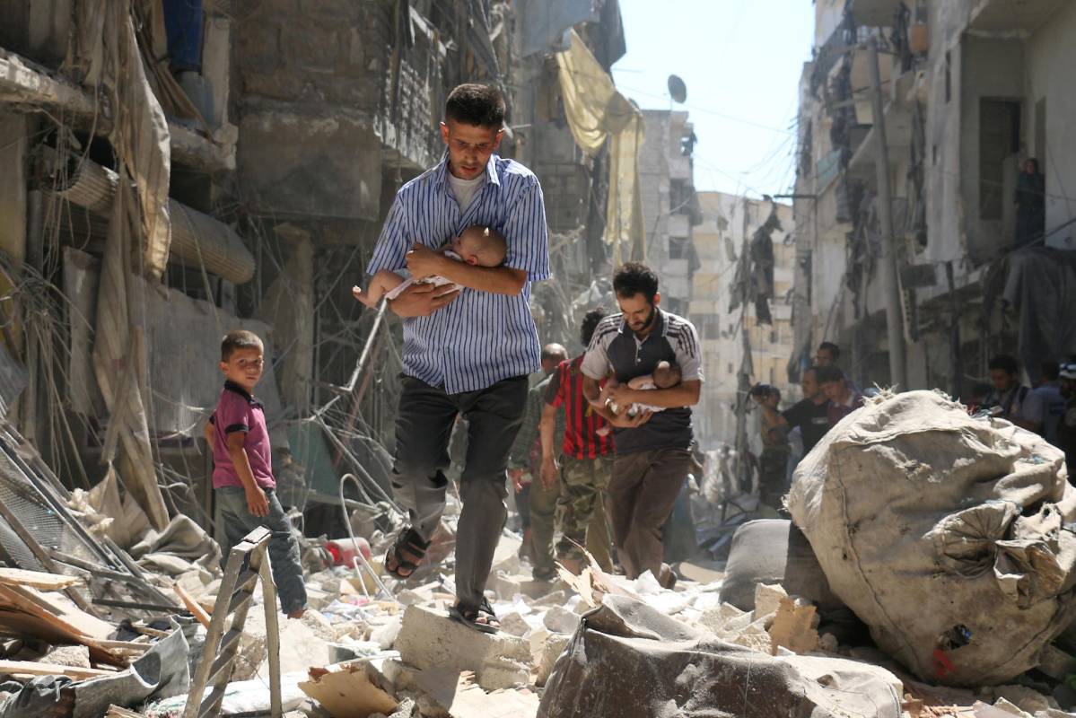 Hombres sirios con unos bebés en brazos se abren camino a través de los escombros de edificios destruidos tras un ataque aéreo en el barrio de Salihin de Alepo. Segundo lugar noticias. FOTO Ameer Alhalbi, Agence France-Presse / Cortesía de World Press Photo Foundation