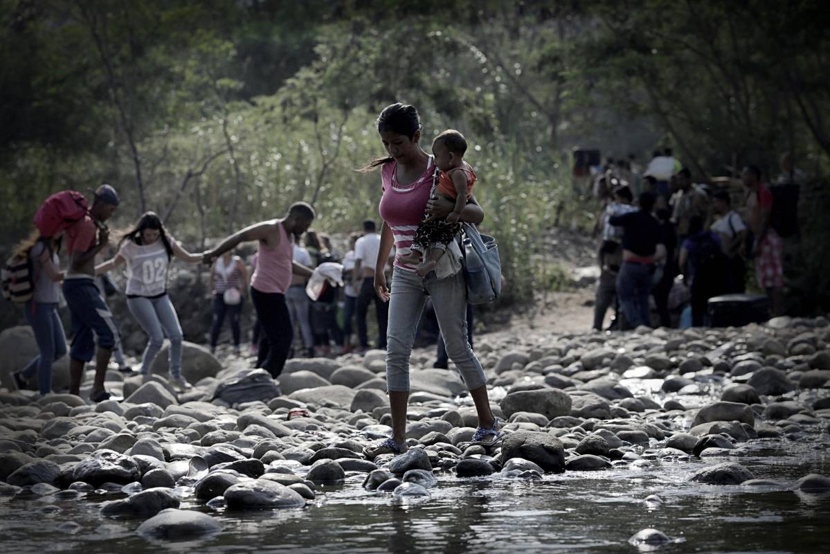 Una mujer con un niño camina por el río Táchira en las afueras de Cúcuta, en la frontera colombiano-venezolana. FOTO REUTERS