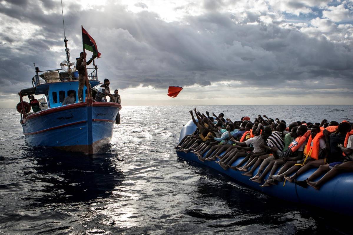 Los pescadores libios lanzan un chaleco salvavidas en un barco de goma lleno de migrantes. Tercer lugar noticias. FOTO Mathieu Willcocks / MOAS.eu / Cortesía de World Press Photo Foundation