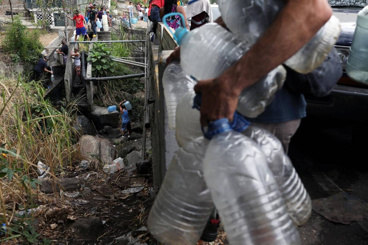 La gente lleva botellas llenas de agua de un río en Caracas, Venezuela, 11 de marzo de 2019. Manaure Quintero.