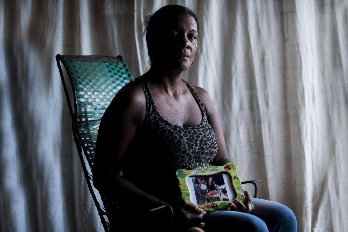 Oneida Figueroa tiene sobre sus piernas un retrato de Angelina Martínez, su hija, una mujer trans que asesinaron el 2 de marzo de 2014. Foto: Charlie Cordero